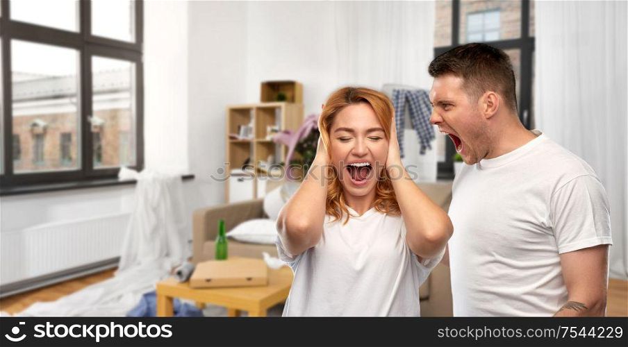 relationship difficulties, conflict and violence concept - unhappy couple having argument over messy home room background. couple having argument over messy home room