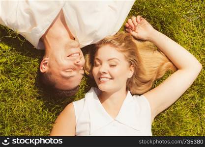 Relationship goals, love forever concept. Man and woman lying on grass having date, enjoying spending romantic time together. Man and woman lying on grass having date