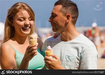 Relationship goals, summer love concept. Man and woman being on date, eating ice cream on beach. Man and woman eating ice cream on beach