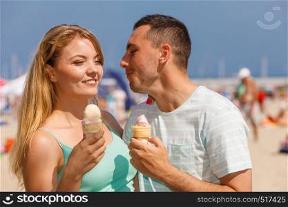 Relationship goals, summer love concept. Man and woman being on date, eating ice cream on beach. Man and woman eating ice cream on beach