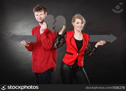 Relationship problem feelings depressing sadness breakup concept. Young pair showing heartbreak symbols. Man with woman holding arrows with broken heart pointing in opposite directions.. Young pair showing heartbreak symbols.