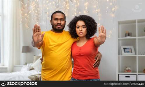relationships and people concept - african american couple hugging and showing stop gesture over home bedroom background. african american couple showing stop gesture