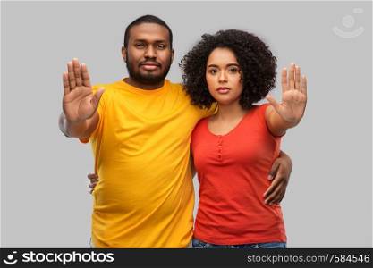 relationships and people concept - african american couple hugging and showing stop gesture over grey background. african american couple showing stop gesture