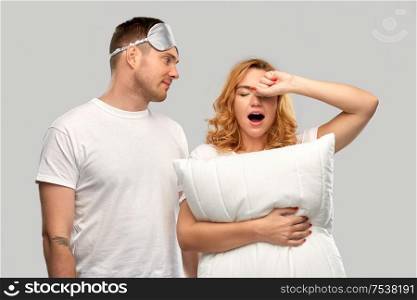 relationships and people concept - couple in white t-shirts with eye sleeping mask and pillow over grey background. couple with eye sleeping mask and pillow