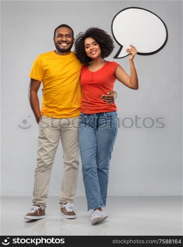 relationships and people concept - happy african american couple holding blank speech bubble over grey background. african american couple with blank speech bubble