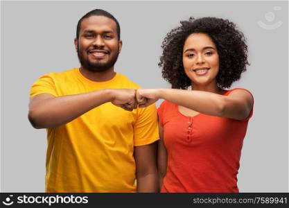 relationships and people concept - happy african american couple making fist bump gesture over grey background. african american couple making fist bump gesture