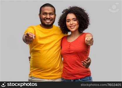 relationships and people concept - happy african american couple pointing to camera over grey background. happy african american couple pointing to camera