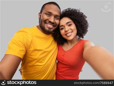 relationships and people concept - happy african american couple taking selfie over grey background. happy african american couple taking selfie