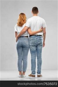 relationships and people concept - happy couple in white t-shirts hugging over grey background from back. happy couple in white t-shirts hugging