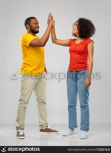 relationships and people concept - happy smiling african american couple making high five over grey background. happy african american couple making high five