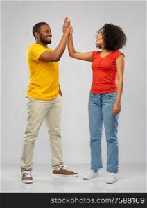 relationships and people concept - happy smiling african american couple making high five over grey background. happy african american couple making high five