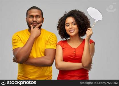 relationships and people concept - happy smiling african american couple with little blank speech bubble over grey background. african american couple with blank speech bubble
