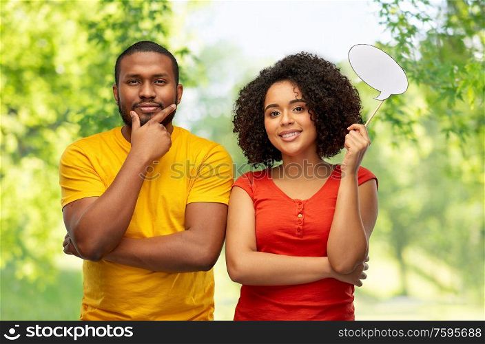 relationships and people concept - happy smiling african american couple with little blank speech bubble over green natural background. african american couple with blank speech bubble