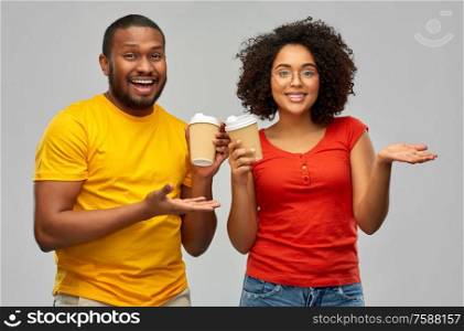 relationships and people concept - happy smiling african american couple with takeaway coffee cups over grey background. happy african american couple with coffee cups