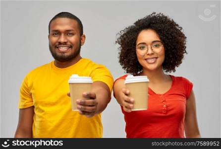 relationships and people concept - happy smiling african american couple with takeaway coffee cups over grey background. happy african american couple with coffee cups