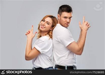 relationships and people concept - portrait of happy couple in white t-shirts making gun gesture over grey background. couple in white t-shirts shirts making gun gesture