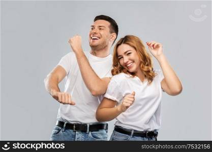 relationships and people concept - portrait of happy couple in white t-shirts dancing over grey background. portrait of happy couple in white t-shirts dancing