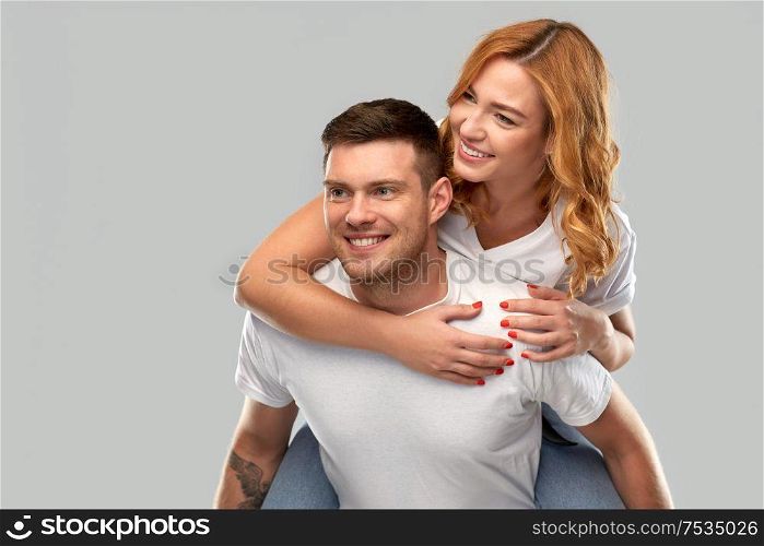 relationships and people concept - portrait of happy couple in white t-shirts having fun over grey background. happy couple in white t-shirts having fun