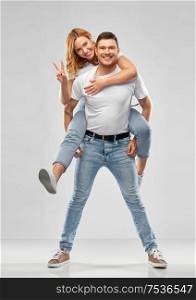 relationships and people concept - portrait of happy couple in white t-shirts having fun and making peace gesture over grey background. happy couple in white t-shirts having fun