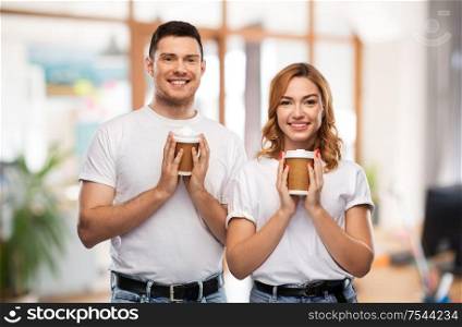 relationships and people concept - portrait of happy couple in white t-shirts with takeaway coffee cups over office background. portrait of happy couple with takeaway coffee cups