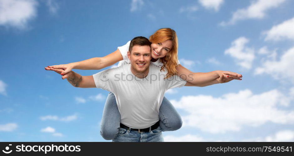 relationships and people concept - portrait of happy couple in white t-shirts having fun over blue sky and clouds background. happy couple in white t-shirts having fun