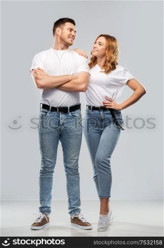 relationships and people concept - portrait of happy couple in white t-shirts over grey background. portrait of happy couple in white t-shirts