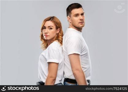 relationships and people concept - portrait of sad couple in white t-shirts over grey background. portrait of sad couple in white t-shirts