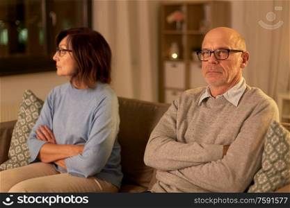 relationships difficulties, problem and people concept - unhappy senior couple sitting on sofa at home. unhappy senior couple sitting on sofa at home