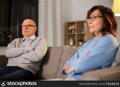 relationships difficulties, problem and people concept - unhappy senior couple sitting on sofa at home. unhappy senior couple sitting on sofa at home