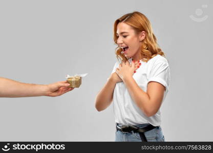 relationships, holiday and valentines day concept - happy couple in white t-shirts with christmas gift over grey background. happy couple in white t-shirts with christmas gift