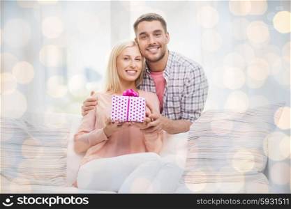 relationships, love, people, birthday and holidays concept - happy man giving woman gift box at home over lights background