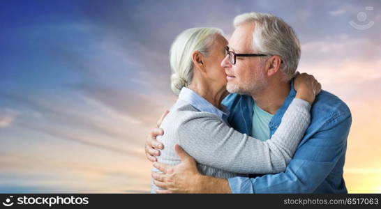 relationships, old age and people concept - happy senior couple hugging over evening sky background. happy senior couple hugging over evening sky. happy senior couple hugging over evening sky