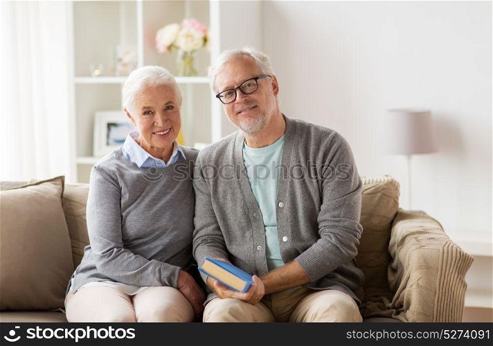 relationships, old age and people concept - happy senior couple sitting on sofa at home. happy senior couple sitting on sofa at home