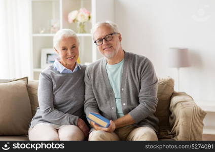 relationships, old age and people concept - happy senior couple sitting on sofa at home. happy senior couple sitting on sofa at home