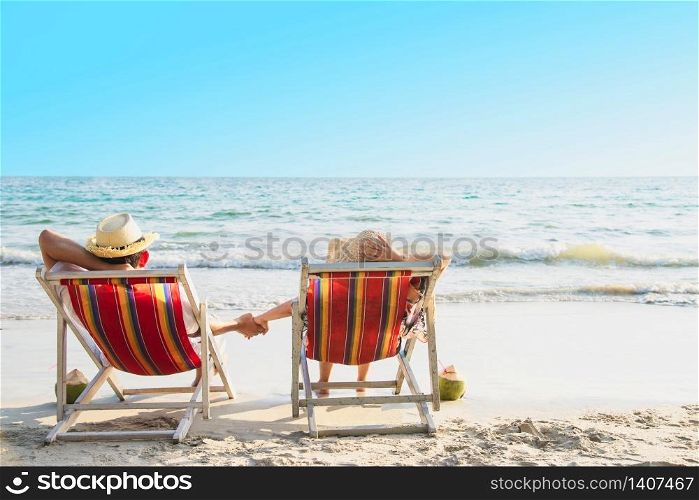 Relax couple lay down on beach chiar with sea wave background - man and woman have vacation at sea nature concept. Relax couple lay down on beach chiar with sea wave background