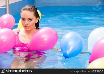 Relax, spa hotel, wellness concept. Woman having fun with balloons in water. Pretty girl relaxing at swimming pool.. Girl relaxing in swimming pool
