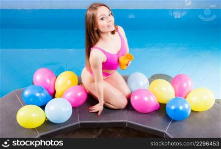 Relax, spa wellness concept. Happy woman having fun with balloons and cocktail drink alcohol. Pretty girl relaxing at swimming pool edge poolside.. Girl relaxing at swimming pool with drink