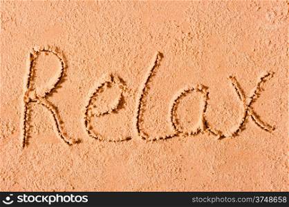 Relax written on wet sand at the sea