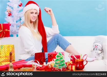 Relaxation during Christmas concept. Blonde young woman in Santa hat sitting on sofa relaxing, enjoying leisure time.. Woman in Santa hat sitting on sofa relaxing