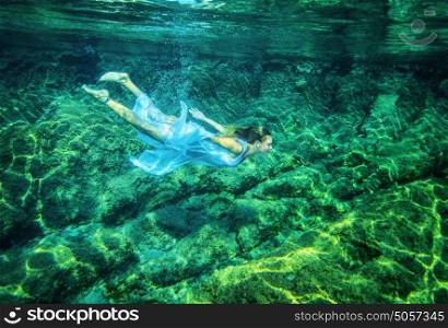Relaxation in the sea, beautiful young female swimming underwater, summer time activity, refreshment and enjoyment concept