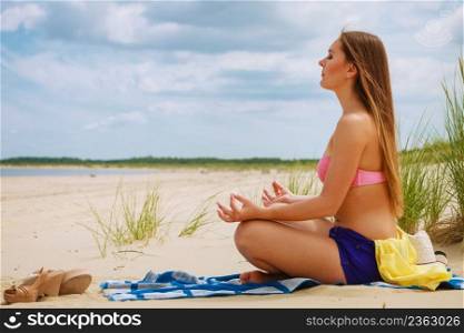 Relaxation time. Young girl spending free time on yoga exercises to relax body and mind. Woman resting on beach in summer.. Woman doing yoga on sandy beach.