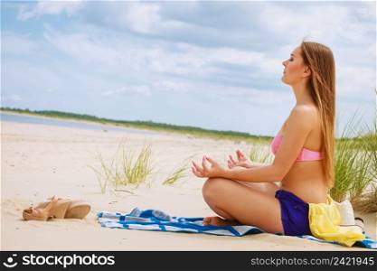 Relaxation time. Young girl spending free time on yoga exercises to relax body and mind. Woman resting on beach in summer.. Woman doing yoga on sandy beach.