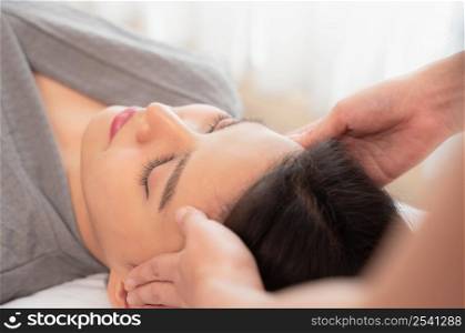 Relaxed and calm girl having spa facial massage in beauty salon. Traditional oriental massage therapy and beauty treatment. Spa skin and body care concept