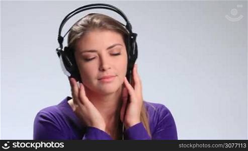 Relaxed beautiful girl with eyes closed listening to the music in earphones. Young attractive woman with headset slowly opening her amazing brown eyes and looking at the camera very determined.