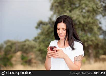 Relaxed brunette woman on the park looking at his mobile