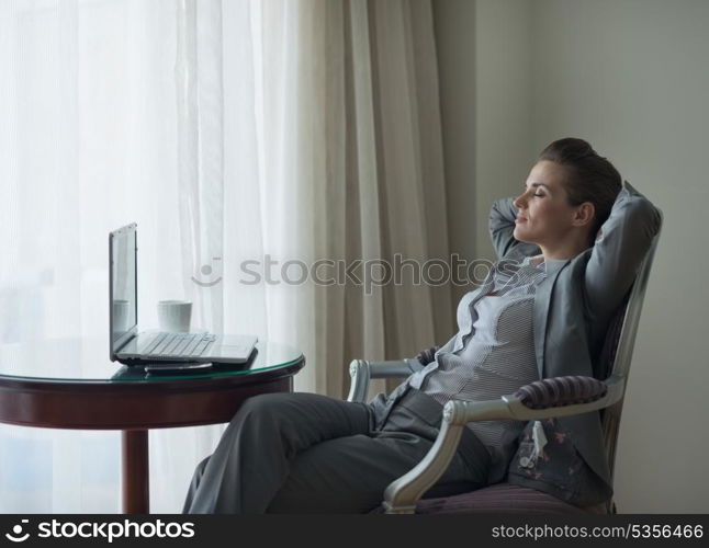 Relaxed business woman sitting in chair in hotel room