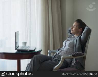 Relaxed business woman sitting in chair in hotel room