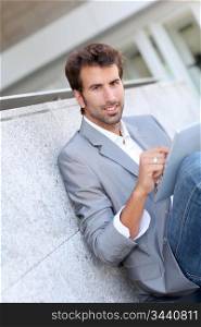 Relaxed businessman sitting outside with tablet