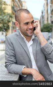 Relaxed businessman with mobile phone in town