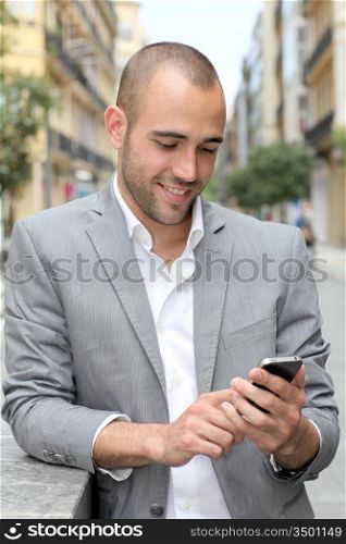 Relaxed businessman with mobile phone in town